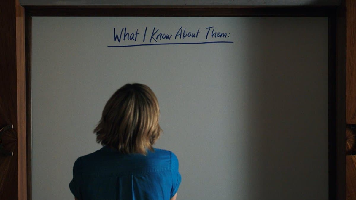 Back of a person in a blue shirt facing a whiteboard titled What I Know About Them